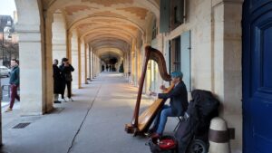 a musician playing the harp under the place des vosges arcs