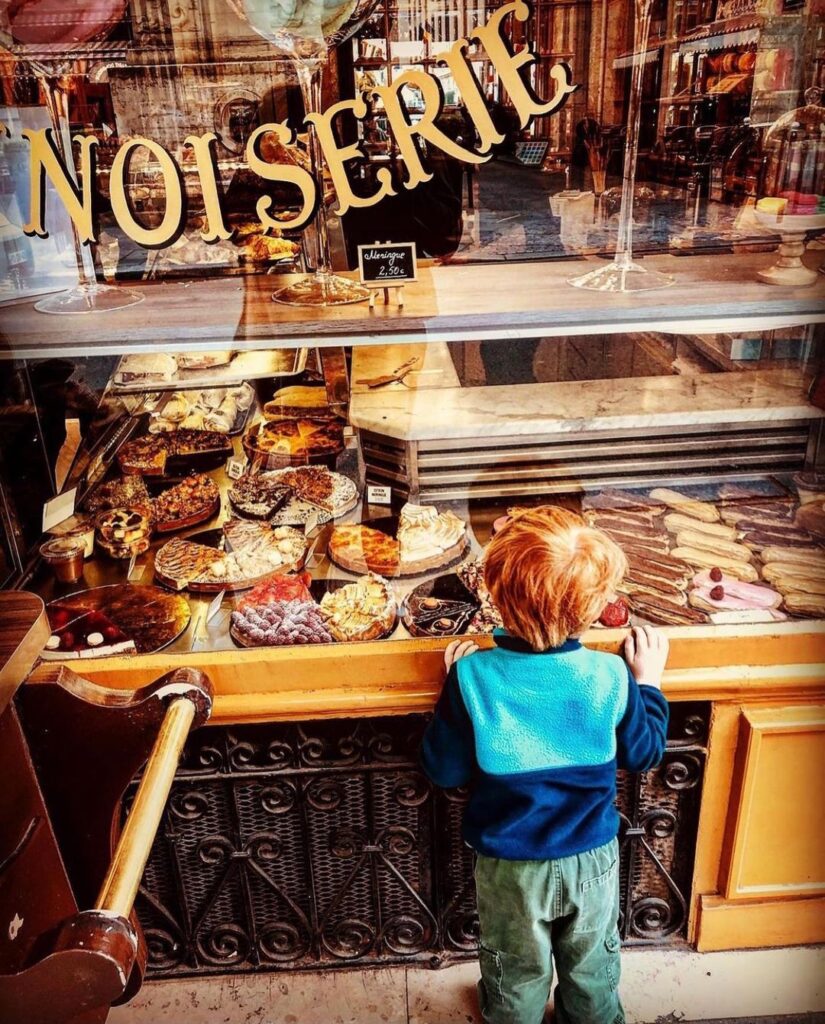 A child looking at pastries in front of a Paris boutique
